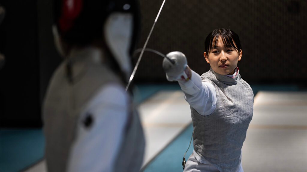 鋭く剣を突き出し相手と対峙する、フェンシング梅津春香選手の競技中の様子